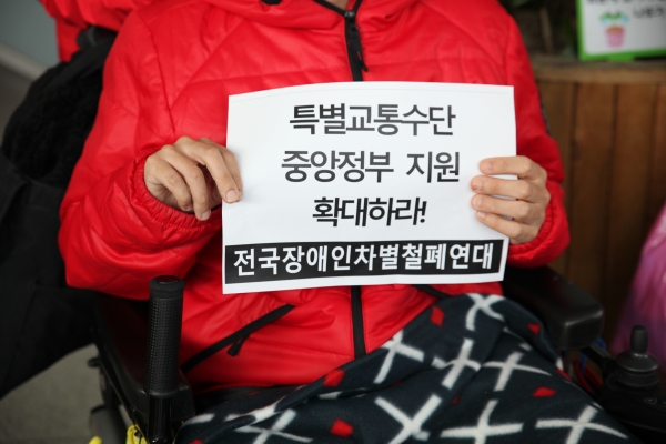 지난 10월 15일 전국장애인차별철폐연대가 주최한 '교통약자 이동편의증진법 전면 개정 행진' 기자회견에서 한 참석자가 피켓을 들고 있다. (사진=서한결 기자)